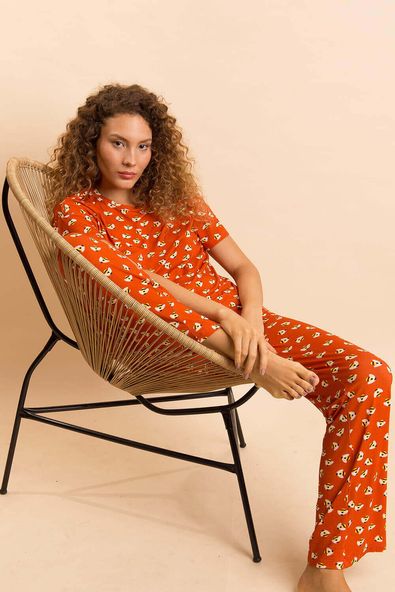 modelo está sentada numa cadeira vestindo o pijama longo de malha na estampa mel
