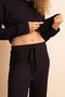 na foto, a modelo está levantando a blusa para mostrar o cós da calça do pijama longo de malha amarração preto