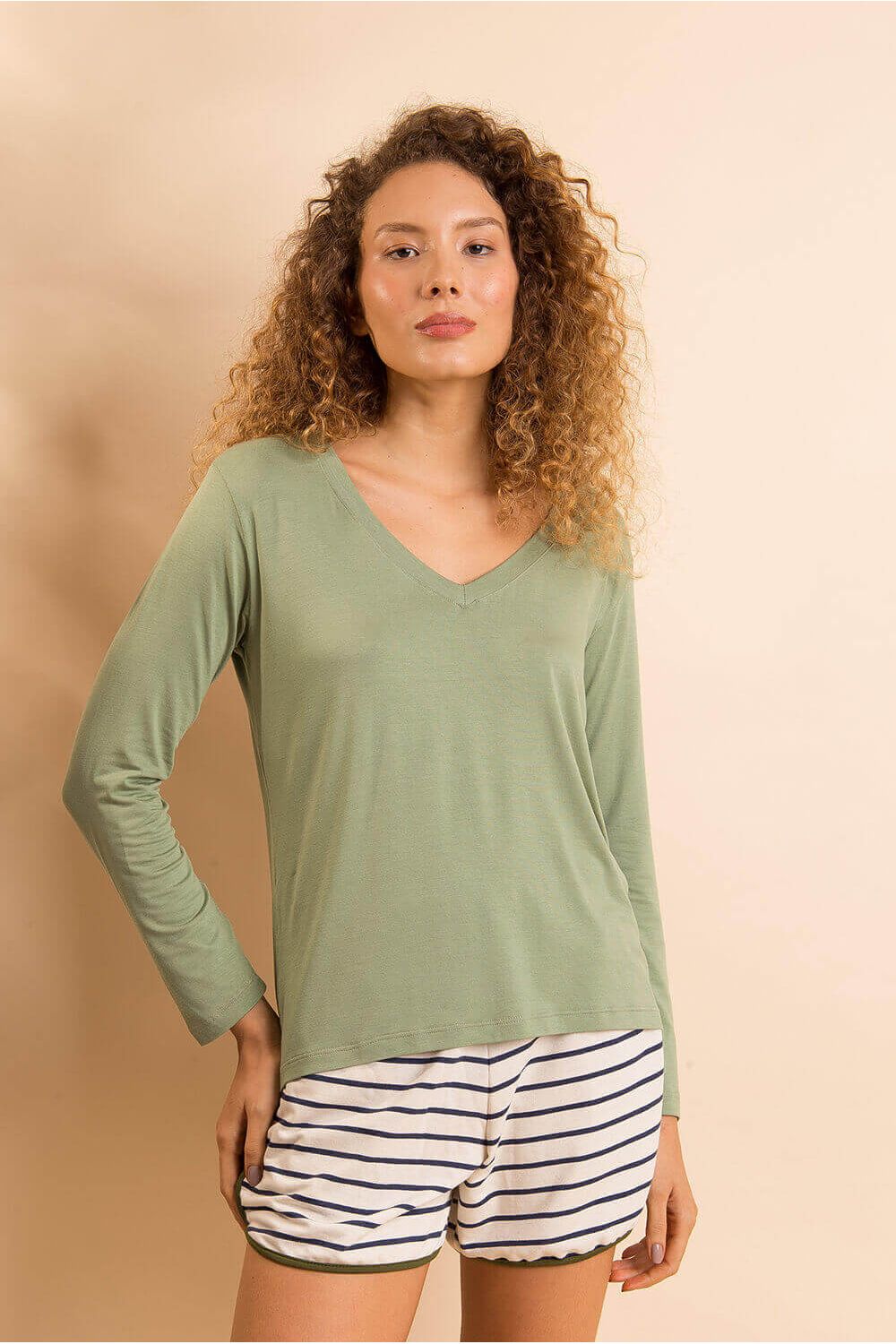 a modelo veste a blusa t-shirt gola v com mangas longas na cor verde botânico de frente