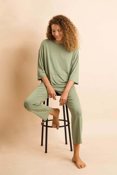 na foto, a modelo está sentada num banco alto vestindo o pijama de malha sete oitavos