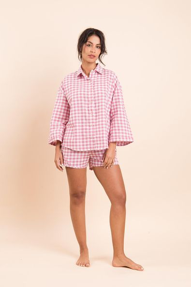 na foto, a modelo está aparecendo de corpo inteiro vestindo o pijama xadrez rosa