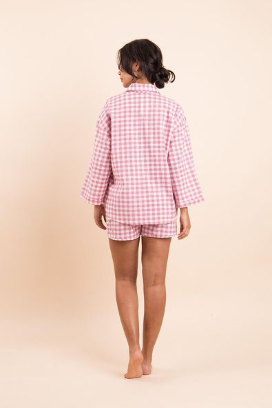 na foto, a modelo está de costas e de corpo inteiro, mostrando o pijama xadrez rosa
