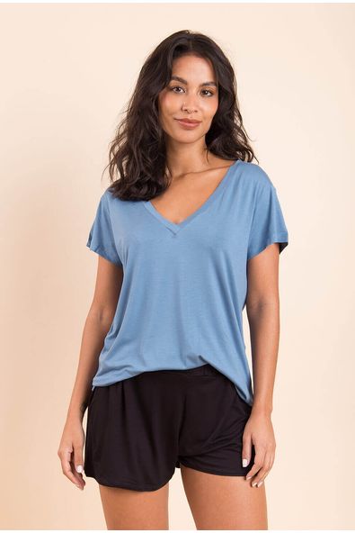 na foto, a modelo está de frente usando a t-shirt gola v na cor azul sereno, ela tem caimento soltinho e mangas curtas