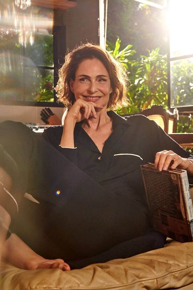 na foto, a atriz e modelo silvia pfeifer está sentada num sofá, com a mão no queixo usando o pijama lenna preto