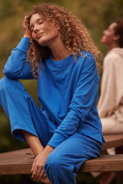 foto da modelo sentada usando o conjunto de moletom azul com friso
